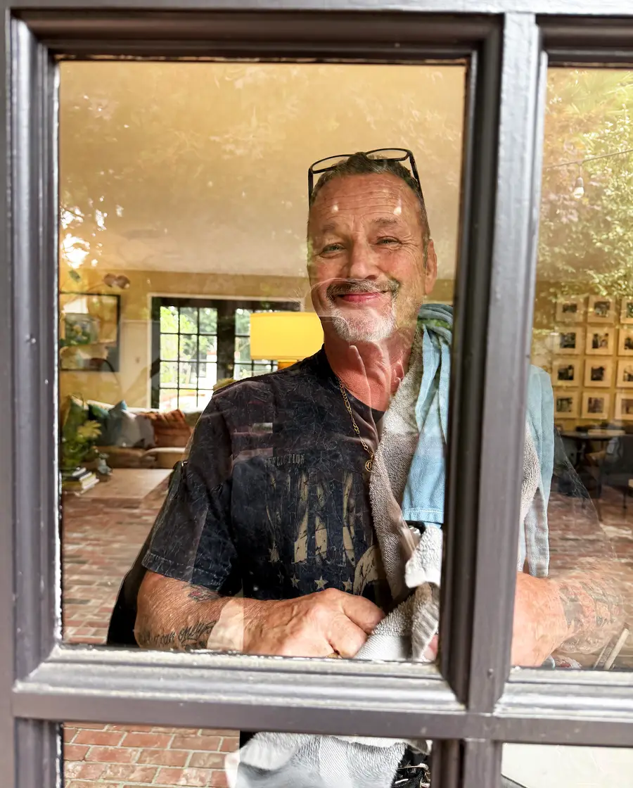 John smiling through a window he has just cleaned