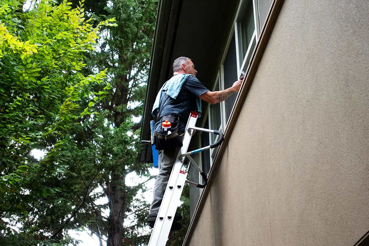 John cleaning a commercial building's windows from a ladder