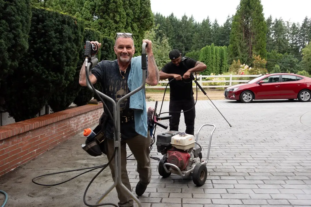 John Speaks with the surface cleaner on a driveway, Ben Cordio on the pressure washer behind him